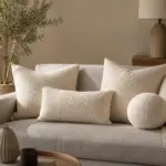 9 Bouclé-Kissen, die jedes Sofa adeln: Lieblingsstücke 2026 Cremeweiße Bouclé-Kissen auf grauem Sofa im Wohnzimmer – Sofa-Styling mit Lumbar und rundem Kissen