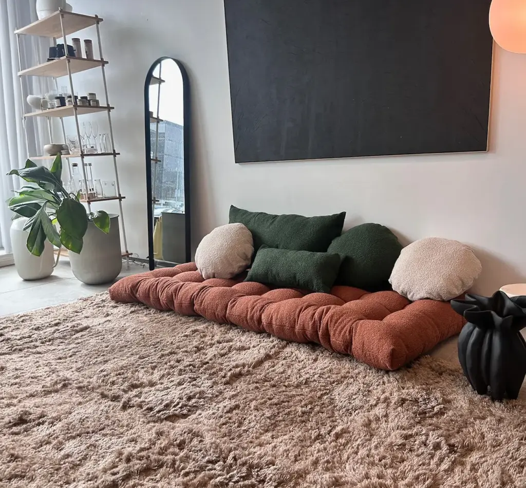 Bouclé-Kissenbezüge in Terrakotta, Dunkelgrün und Cremeweiß auf einem Boden-Lounger mit Hochflorteppich